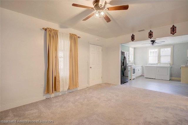 unfurnished living room with light colored carpet, washer and clothes dryer, and ceiling fan