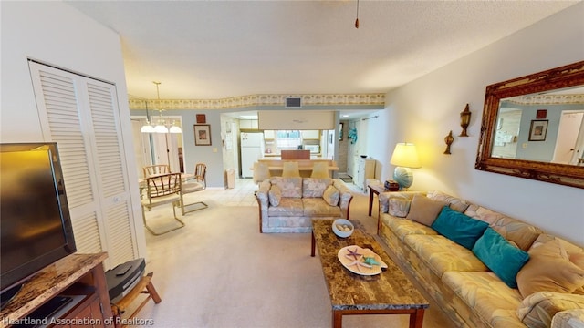 carpeted living room with a notable chandelier