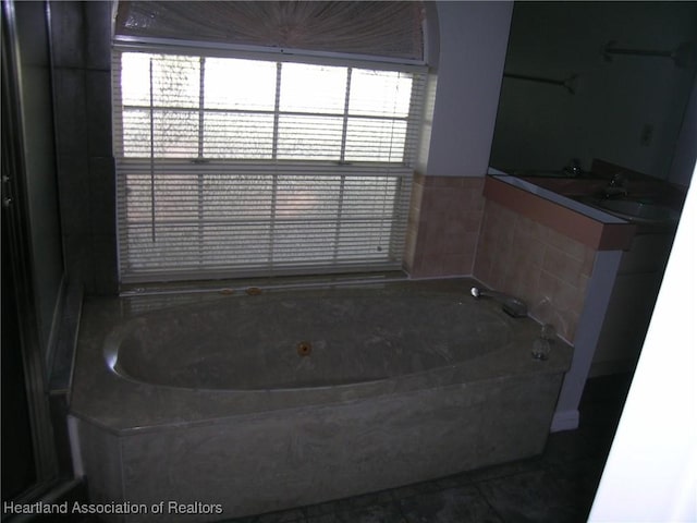 full bathroom featuring tile patterned flooring, a garden tub, and a sink