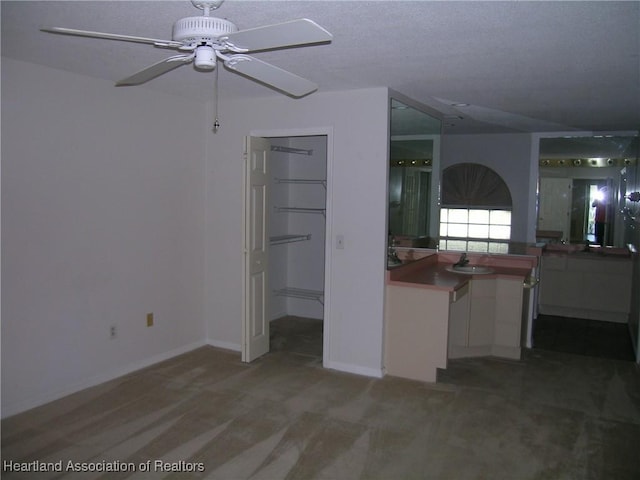 interior space with a sink, baseboards, and ceiling fan