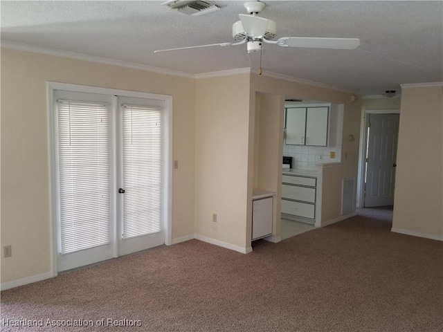 spare room with carpet floors, visible vents, and crown molding