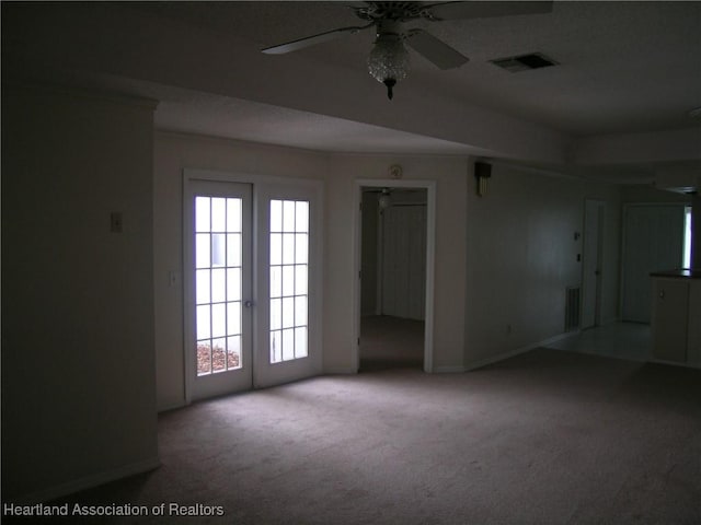 carpeted empty room featuring baseboards, visible vents, and a ceiling fan