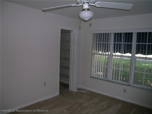 carpeted empty room with ceiling fan and baseboards