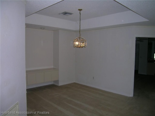 unfurnished room with a raised ceiling, visible vents, and a notable chandelier