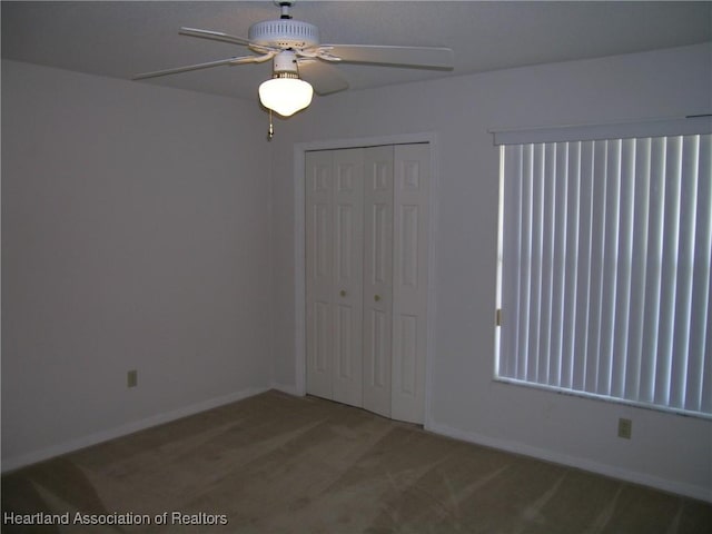 unfurnished bedroom with a closet, carpet flooring, a ceiling fan, and baseboards