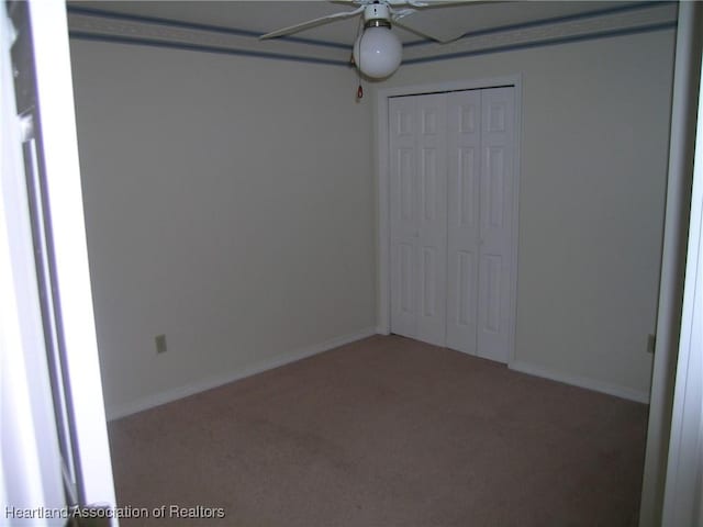 unfurnished bedroom featuring ceiling fan, a closet, carpet, and baseboards