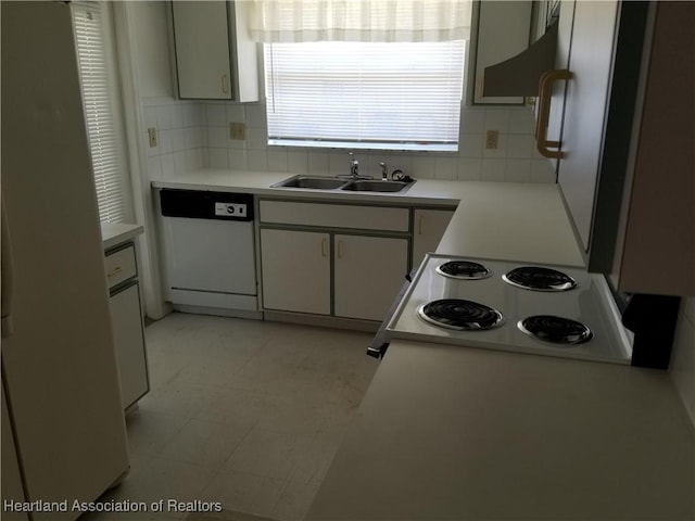 kitchen featuring decorative backsplash, light countertops, dishwasher, and a sink