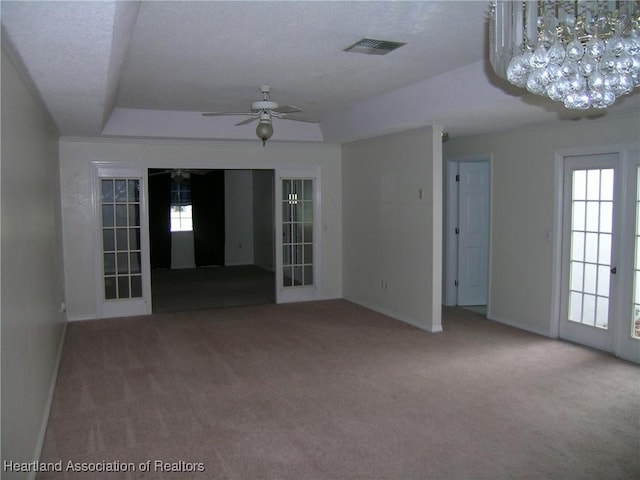 carpeted spare room with visible vents, a raised ceiling, and french doors