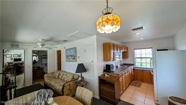 kitchen featuring pendant lighting, white refrigerator, sink, ceiling fan, and light tile patterned flooring