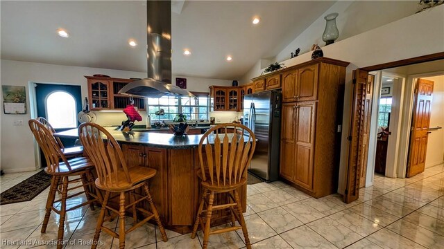 kitchen featuring lofted ceiling, a breakfast bar area, gas stovetop, stainless steel fridge with ice dispenser, and island exhaust hood