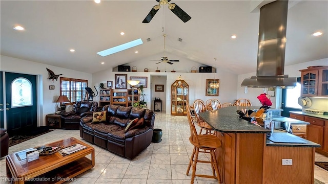 living room featuring ceiling fan, a healthy amount of sunlight, and lofted ceiling with skylight