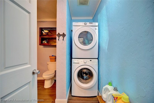 laundry room featuring hardwood / wood-style floors, stacked washer / drying machine, and ornamental molding