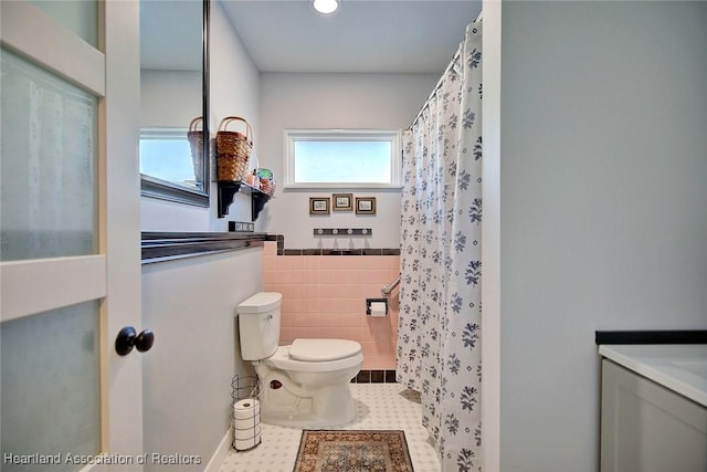 bathroom with tile patterned flooring, toilet, and tile walls