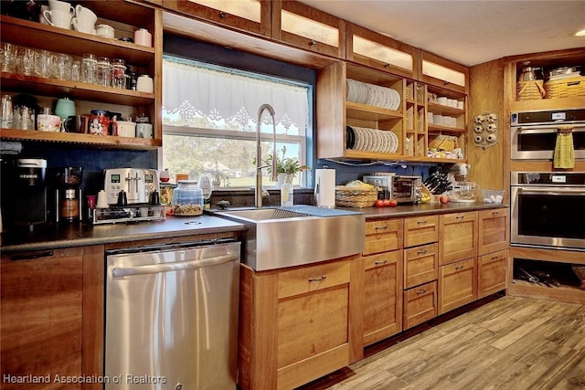 kitchen with appliances with stainless steel finishes, light hardwood / wood-style flooring, and sink