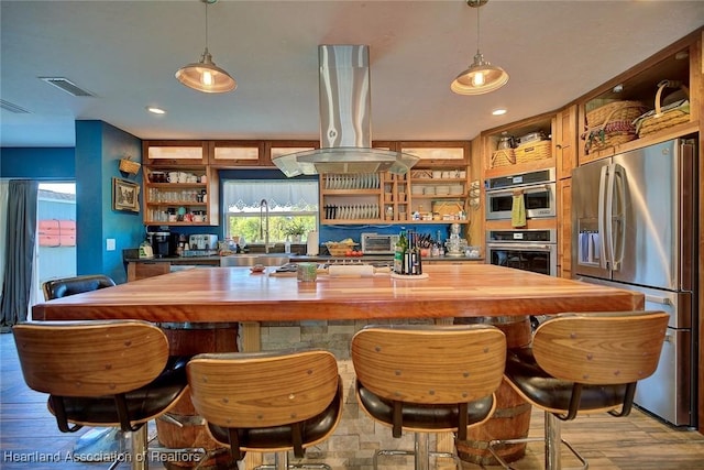 bar with built in shelves, stainless steel appliances, island range hood, sink, and light hardwood / wood-style floors