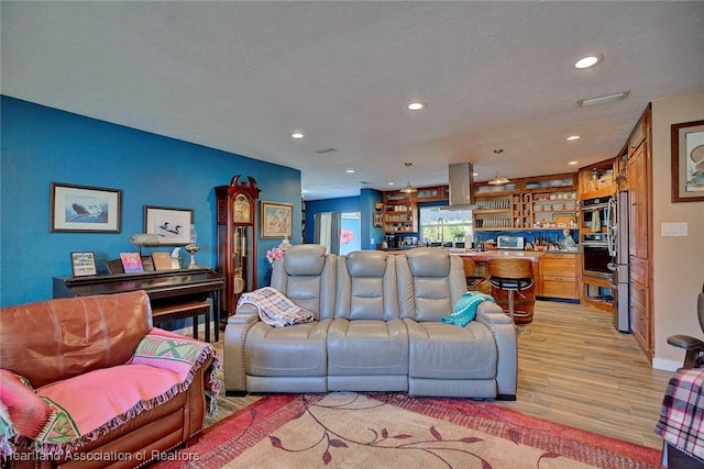 living room featuring light hardwood / wood-style floors, built in features, and a textured ceiling