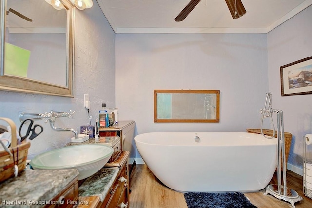 bathroom featuring a tub, crown molding, hardwood / wood-style floors, and vanity