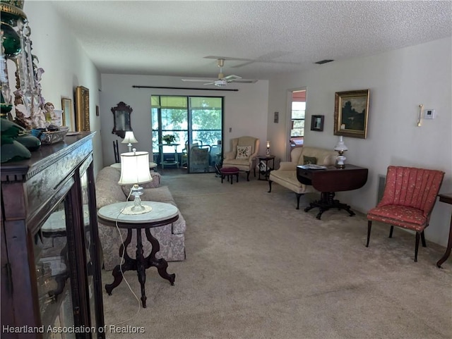 carpeted living room with ceiling fan and a textured ceiling