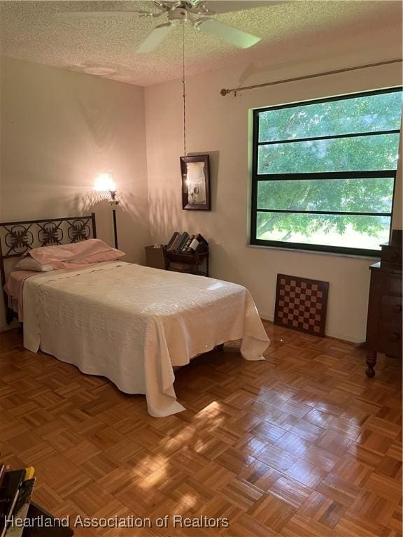 bedroom featuring parquet flooring, a textured ceiling, and ceiling fan