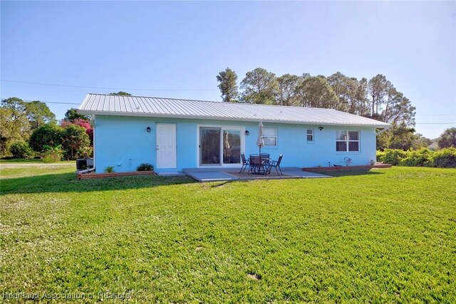 back of house with a patio and a lawn