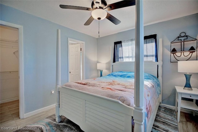 bedroom with light hardwood / wood-style floors, a spacious closet, ceiling fan, and a closet