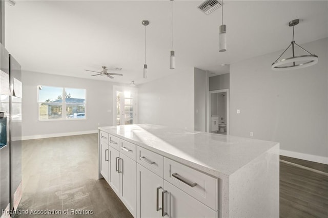 kitchen featuring a kitchen island, decorative light fixtures, white cabinets, dark hardwood / wood-style flooring, and light stone countertops