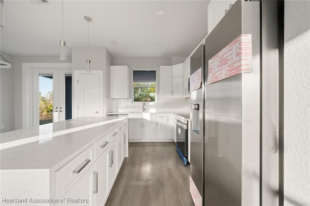 kitchen featuring a kitchen island, sink, white cabinets, stainless steel fridge, and hanging light fixtures