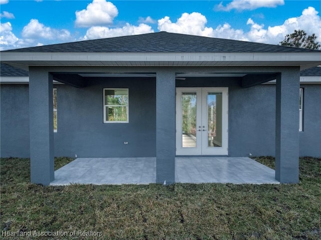 back of property with a patio, a lawn, and french doors