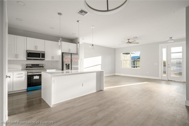 kitchen with pendant lighting, light hardwood / wood-style flooring, white cabinetry, stainless steel appliances, and a kitchen island