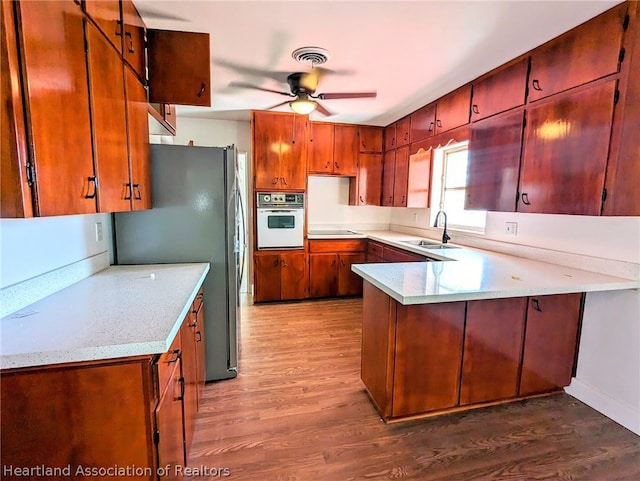 kitchen with white oven, dark hardwood / wood-style flooring, stainless steel fridge, and sink