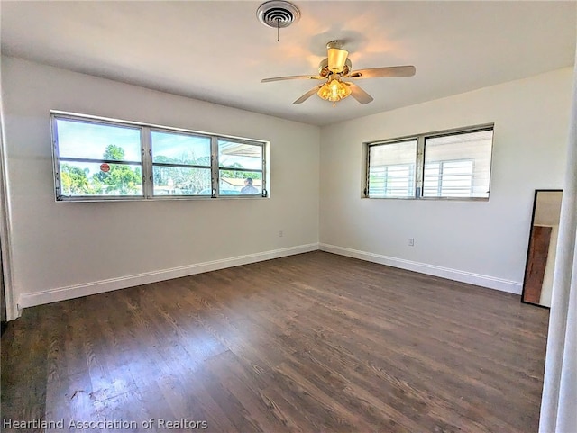 spare room with a healthy amount of sunlight, ceiling fan, and dark wood-type flooring