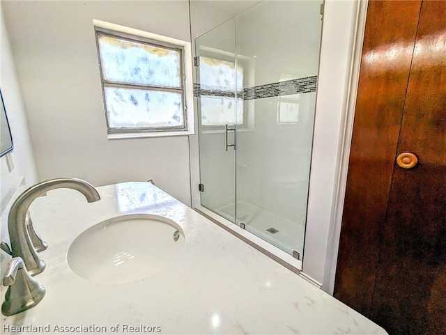 bathroom featuring a shower with door and vanity