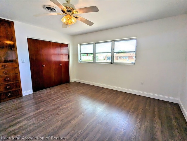 unfurnished bedroom featuring ceiling fan, dark wood-type flooring, and a closet