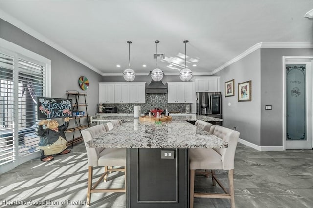 kitchen featuring stainless steel fridge, pendant lighting, white cabinetry, and a large island