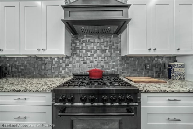 kitchen featuring stainless steel range, decorative backsplash, white cabinets, and custom exhaust hood