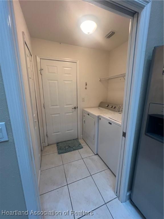 clothes washing area with light tile patterned floors and washer and clothes dryer