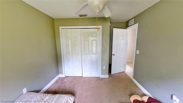 unfurnished bedroom with light carpet, a closet, and ceiling fan