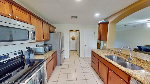 kitchen with sink, light tile patterned floors, light stone countertops, ornamental molding, and appliances with stainless steel finishes