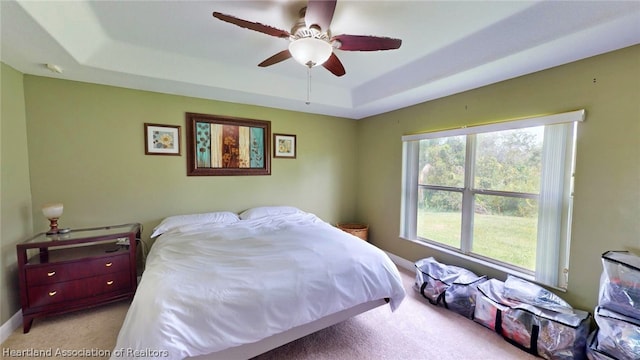 bedroom featuring a tray ceiling, ceiling fan, and light carpet