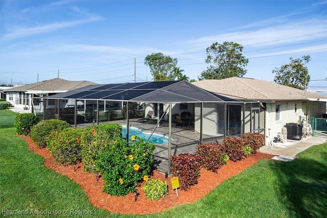 back of house featuring glass enclosure, a patio area, and a lawn