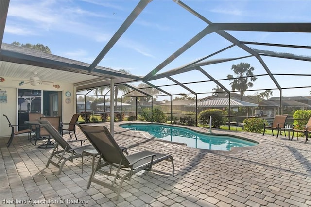 view of pool featuring glass enclosure, a patio, and ceiling fan