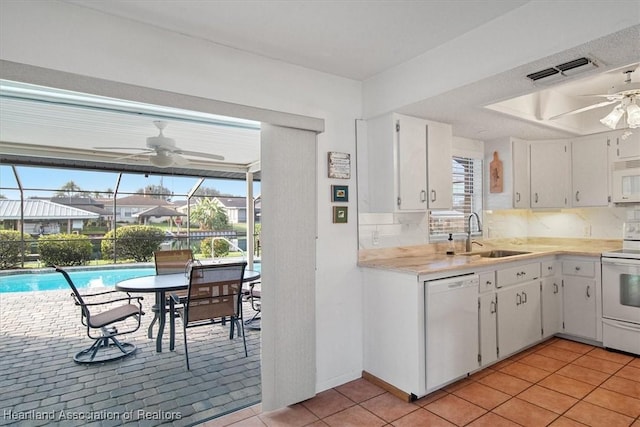 kitchen featuring sink, white appliances, white cabinetry, and light tile patterned floors