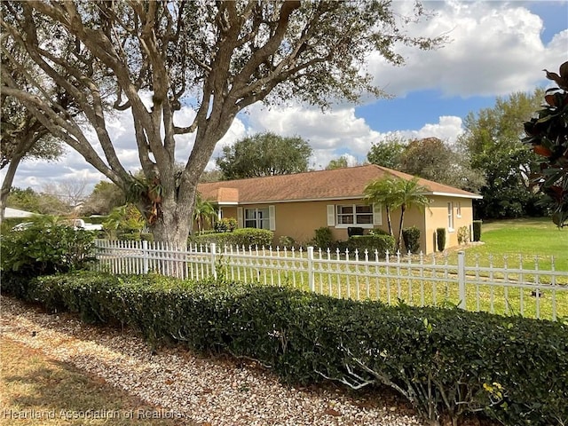 ranch-style home featuring a fenced front yard, a front yard, and stucco siding