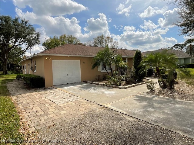 ranch-style home featuring an attached garage, roof with shingles, concrete driveway, and stucco siding