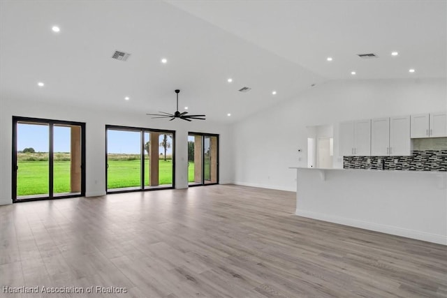 unfurnished living room with ceiling fan, high vaulted ceiling, and light hardwood / wood-style flooring