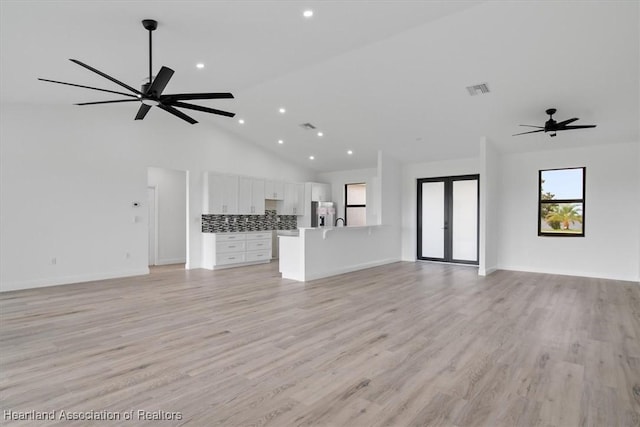 unfurnished living room featuring french doors, ceiling fan, high vaulted ceiling, and light wood-type flooring