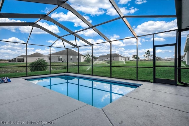 view of pool featuring a patio area, glass enclosure, and a lawn