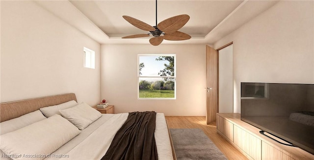 bedroom featuring light wood-type flooring, a raised ceiling, and ceiling fan