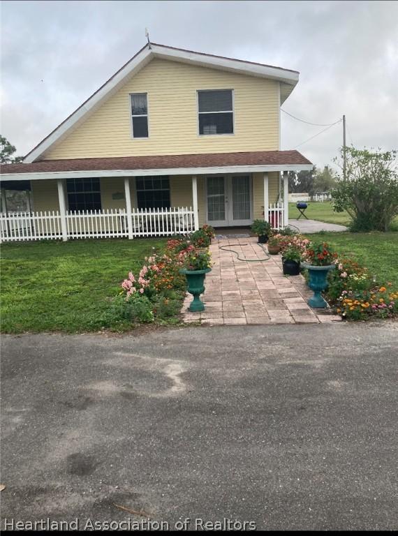 view of front facade with french doors and a front lawn