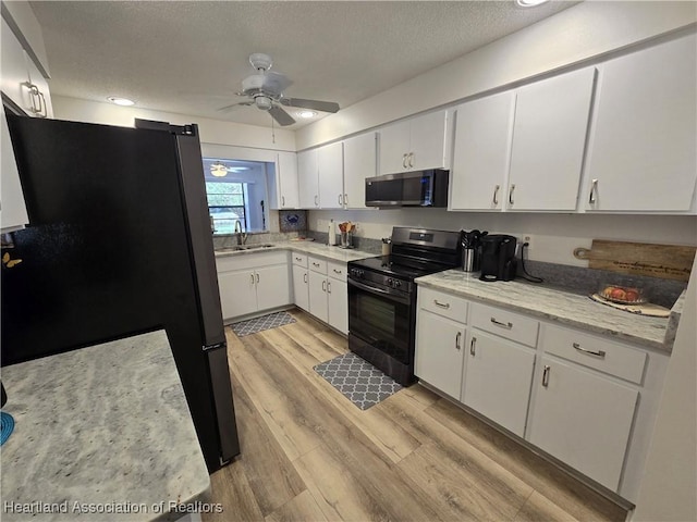 1725 Amber Ln, Lake Placid, FL 33852 - kitchen with stainless steel appliances, ceiling fan, white cabinets, light wood finished floors, and a textured ceiling